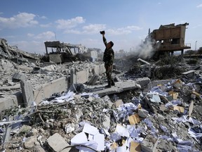 A Syrian soldier films the damage of the Syrian Scientific Research Center which was attacked by U.S., British and French military strikes to punish President Bashar Assad for suspected chemical attack against civilians, in Barzeh, near Damascus, Syria, Saturday, April 14, 2018. The Pentagon says none of the missiles filed by the U.S. and its allies was deflected by Syrian air defenses, rebutting claims by the Russian and Syrian governments. Lt. Gen. Kenneth McKenzie, the director of the Joint Staff at the Pentagon, also says there also is no indication that Russian air defense systems were employed early Saturday in Syria.