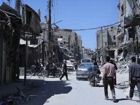 People walk among damaged buildings in the town of Douma, the site of a suspected chemical weapons attack, near Damascus, Syria, Monday, April 16, 2018. Two days after Syrian troops declared Douma liberated from opposition fighters, a tour in the city showed the wide destruction it has suffered since falling under rebel control six years ago.