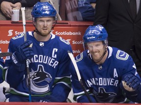 Vancouver Canucks forwards Henrik Sedin (left) and Daniel Sedin look on from the bench against the Vegas Golden Knights on April 3.