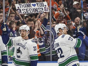 Vancouver Canucks' Henrik Sedin (33) and Daniel Sedin (22) acknowledge the crowd's cheers during a break in their game against the Oilers at Rogers Place in Edmonton on Saturday night.