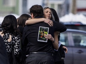 Mourners hug after the funeral for Humboldt Broncos player Conner Lukan in Slave Lake, Alta. on Wednesday, April 18, 2018.