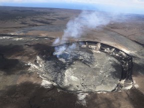 ADDS THE PHOTOGRAPHER'S NAME - In this April 23, 2018 photo provided by the U.S. Geological Survey, a helicopter view of Kilauea Volcano's Halemaumau crater shows the extent of the largest overflow (silver gray) of the lava lake in Hawaii Volcanoes National Park on Hawaii's Big Island. Lava from Kilauea's summit lava lake continues to overflow intermittently out of its Overlook crater onto the floor of Halemaumau Crater, after recording its largest overflow since the summit vent opened up 10 years ago. Hawaiian Volcano Observatory scientists noted overflows again Wednesday morning around 8:30 a.m., after two episodes of activity Tuesday.