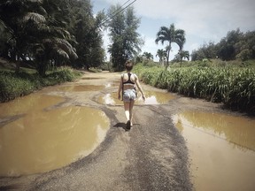 In this April 18, 2018 photo provided by Jan Snarksi, Snarski's wife Emilie Johnson carries their baby while walking toward Anahola Beach in Anahola on the island of Kauai in Hawaii. Kauai residents and businesses are still cleaning up from devastating floods and record rains, but community leaders are urging tourists to visit so residents don't suffer an economic calamity on top of the natural one.