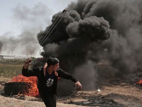 A Palestinian hurls stones at Israeli troops during a protest at the Gaza Strip's border with Israel on Friday, April 6, 2018.