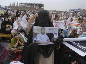 A woman from a Pakistani tribal area displays a picture of a missing family member during a rally in the northwestern city of Peshawar, Pakistan, Sunday, April 8, 2018. Thousands of people from Pakistan's tribes have rallied in Peshawar demanding the release of scores of suspects being held by authorities on alleged links to militants.