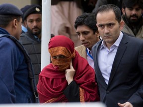 FILE - In this Jan. 6, 2017 file photo, the wife, center, of a judge is escorted from the Supreme Court by her brother in Islamabad, Pakistan. A Pakistani high court on Tuesday, April 17, 2018 has convicted a former judge and his wife of torturing a 10-year-old child working as a servant at their home and sentenced them to a year in prison.
