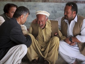 People comfort a man who lost his son in a deadly shooting incident outside a hospital in Quetta, Pakistan, Sunday, April 22, 2018. Police in Pakistan said gunmen have killed multiple Shiites, the latest in a recent series of attacks on the religious minority.