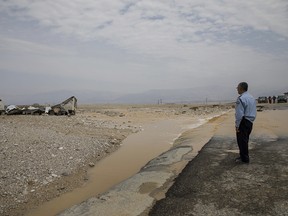Israeli policeman stands by a truck that was swept in flood near Tzin river by the Dead Sea, Israel, Friday, April 27, 2018.