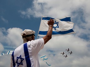 An Israeli waves toward an air force flyover during Israel's 64th Independence Day anniversary celebrations in Tel Aviv in a file photo from 2012.