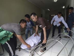 In this Monday, April 9, 2018, photo, family move the body of a victim who died from drinking poisonous bootleg liquor at a hospital in Cicalengka, West Java, Indonesia. Indonesian authorities say more people have died from toxic bootleg liquor, raising the toll this month to nearly 80 and highlighting how attempts to curb legal alcohol appear to have tragically backfired.