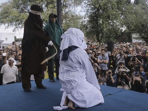 A Shariah law official whips a woman who is convicted of prostitution during a public caning outside a mosque in Banda Aceh, Indonesia, Friday, April 20, 2018. Indonesia's deeply conservative Aceh province on Friday caned several unmarried couples for showing affection in public and two women for prostitution before an enthusiastic audience of hundreds. The canings were possibly the last to be carried out before large crowds in Aceh after the province's governor announced earlier this month that the punishments would be moved indoors.