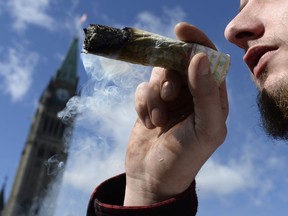 A man smokes a marijuana joint during the annual 4/20 marijuana celebration on Parliament Hill in Ottawa on Friday, April 20, 2018.