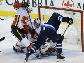 Andrew Coop of the Winnipeg Jets bangs away at a loose puck in front of Calgary Flames' goaltender Jon Gillies during NHL action Thursday in Winnipeg. The Jets were 2-1 winners as they prepare to face the Minnesota Wild in the first round of the playoffs.