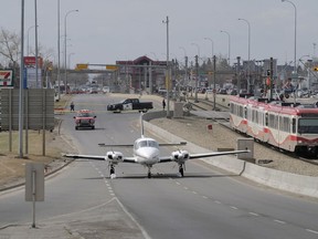 A twin-engine plane sits in an area taped-off by police on 36th Street NE in Calgary on Wednesday, April 25, 2018. A small plane carrying six people made an emergency landing on a Calgary street on Wednesday morning. Police say the twin-engine plane was coming in from the south, heading for a landing at the Calgary airport, when a pilot radioed in that the aircraft was low on fuel.