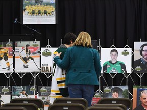Mourners comfort each other as they look at photographs prior to a vigil at the Elgar Petersen Arena, home of the Humboldt Broncos, to honour the victims of a fatal bus accident in Humboldt, Sask. on Sunday, April 8, 2018.