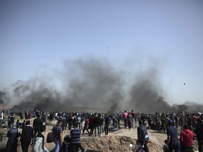 Palestinian protesters gather as black smoke is seen from burning tires during a protest at the Gaza Strip's border with Israel, Friday, April 6, 2018.