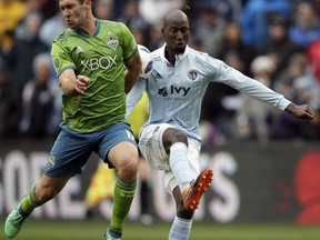 Seattle Sounders defender Will Bruin, left, blocks a kick by Sporting Kansas City defender Ike Opara, right, during the first half of an MLS soccer match in Kansas City, Kan., Sunday, April 15, 2018.