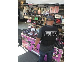 This April 12, 2018, photo released by the Los Angeles Police Department shows a Los Angeles police officer with counterfeit cosmetics seized in the Santee Alley area of Los Angeles. $700,000 worth of counterfeit cosmetics seized from vendors in downtown's fashion district have tested positive for bacteria, lead and traces of animal feces, Los Angeles police said Monday, April 16, 2018.