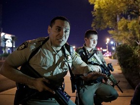 FILE - In this Oct. 1, 2017 file photo, police officers advise people to take cover near the scene of a shooting near the Mandalay Bay resort and casino on the Las Vegas Strip in Las Vegas. The Nevada Supreme Court has rejected a Las Vegas police bid to delay the release of records about the Oct. 1 mass shooting, including officer body camera videos, 911 recordings, evidence logs and written interview reports. Five of seven justices said Friday, April 27, 2018 the Las Vegas Metropolitan Police Department should make public the records that several media entities hope will shed light on the investigation of the deadliest mass shooting in modern U.S. history.
