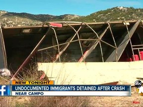In this Saturday, April 7, 2018 image taken from video provided by KGTV ABC10 News shows authorities checking a horse trailer overturned on a California highway near Campo, Calif., just north of the border with Mexico. The trailer was carrying about 18 people who entered the country illegally, who were inside and were hurt in the crash.  Injuries were described as moderate and minor. The California Highway Patrol says a witness reported that the two-axle trailer being hauled by a pickup truck began to fishtail and eventually tipped onto its right side along northbound Interstate 8. The San Diego Union Tribune says authorities rounded up most, if not all, of the people involved. (KGTV ABC10 News via AP)
