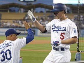 Los Angeles Dodgers' Corey Seager (5) is congratulated by manager Dave Roberts after hitting a solo home run during the first inning of a baseball game against the Oakland Athletics, Tuesday, April 10, 2018, in Los Angeles.