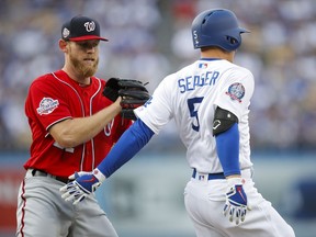 Washington Nationals starting pitcher Stephen Strasburg, left, tags out Los Angeles Dodgers' Corey Seager during the first inning of a baseball game Saturday, April 21, 2018, in Los Angeles.