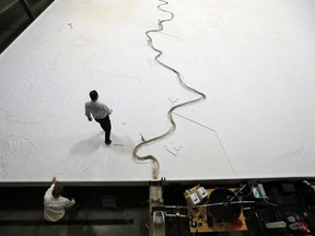 In this March 29, 2018 photo, Rudy Simoneaux, above, engineer manager for the Louisiana Coastal Protection and Restoration Authority, and Joseph McClatchy, coastal resources program specialist, walk on a replica of the lower Mississippi River in Baton Rouge, La. The model will help experts study the river and how sediment can be used from it to fight coastal erosion.