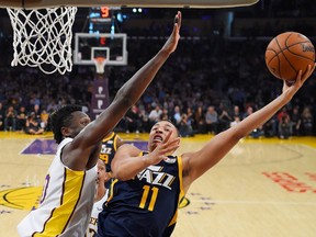 Utah Jazz guard Dante Exum, right, of Australia, shoots as Los Angeles Lakers forward Julius Randle defends during the first half of an NBA basketball game Sunday, April 8, 2018, in Los Angeles.
