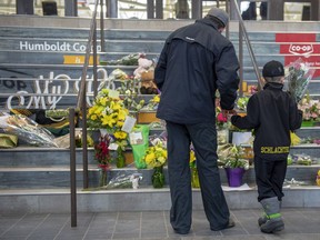 People gather at a memorial set up on the stairs that lead to Elgar Petersen Arena in Humboldt, Sask. on Saturday, April 7, 2018. Investigators are still trying to piece together what happened when a tractor-trailer collided with a hockey team bus at a Saskatchewan highway intersection in a horrific crash that killed 15 people, including players and the coach of the Humboldt Broncos.