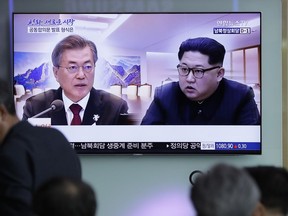 People watch a TV screen showing file footage of South Korean President Moon Jae-in and North Korean leader Kim Jong Un during a news program ahead of the inter-Korean summit at the Seoul Railway Station in Seoul, South Korea, Thursday, April 26, 2018. North Korean leader Kim Jong Un and South Korean President Moon Jae-in will plant a commemorative tree and inspect an honor guard together after Kim walks across the border Friday for their historic summit, Seoul officials said Thursday.
