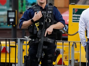 FILE - In this Friday, Sept. 15, 2017 file photo, an armed police officer stands nearby after an incident on a tube train in London. British officials say armed and undercover police officers will patrol train stations with routes leading to Windsor when Prince Harry marries Meghan Markle on May 19. British Transport Police said Thursday, April 19, 2018 there will be a visible deployment of officers along with canine units and specialists trained to detect dangerous behavior.