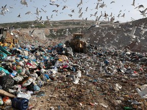 FILE - In this Wednesday, Feb. 2, 2018 file photo, earthmovers push mountains of garbage as seagulls fly over the country's largest landfill at Fyli on the outskirts of Athens. The British government is planning a consultation about a possible bill to end the use of plastic straws, drink stirrers and cotton buds - and is urging other Commonwealth nations to ban the practice as well.  Prime Minister Theresa May said Thursday, April 19, 2018 that "plastic waste is one of the greatest environmental challenges facing the world."