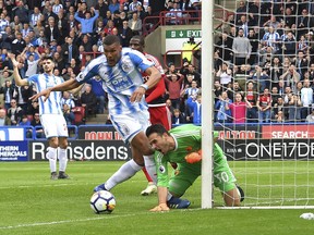 Huddersfield Town's Collin Quaner, center, has an attempt on goal stopped by Watford's goalkeeper Orestis Karnezis during their English Premier League soccer match at the John Smith's Stadium, Huddersfield, England, Saturday, April 14, 2018.