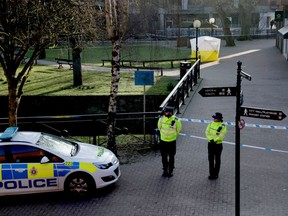FILE - In this Wednesday, March 7, 2018 file photo, police officers guard a cordon around a police tent covering the the spot where former Russian double agent Sergei Skripal and his daughter were found critically ill Sunday following exposure to an "unknown substance" in Salisbury, England. British officials said Tuesday April 17, 2018, the nerve agent used to poison former Russian spy Sergei Skripal and his daughter was delivered in liquid form, and it will take months to remove all traces of the toxin.