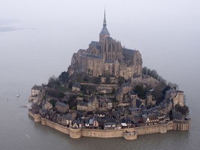 FILE - In this March 21, 2015 file photo, a high tide submerges a narrow causeway leading to the Mont Saint-Michel, on France's northern coast. Authorities are evacuating tourists and others from the Mont-Saint-Michel abbey and monument in western France on Sunday April 22, 2018, after a visitor apparently threatened to attack security services. (AP Photo) FRANCE OUT