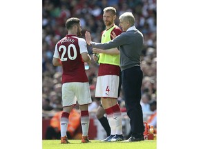 Arsenal manager Arsene Wenger talks to Shkodran Mustafi, left, during the English Premier League soccer match against West Ham United at the Emirates Stadium, London, Sunday April 22, 2018.