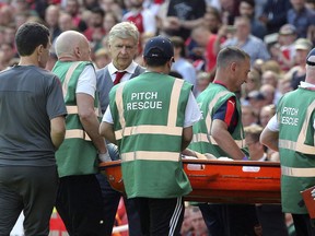 Arsenal's Arsene Wenger watches as Mohamed Elneny leaves the pitch injured on a stretcher during the English Premier League soccer match against West Ham United at the Emirates Stadium, London, Sunday April 22, 2018.