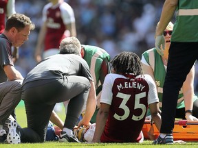 Arsenal's Mohamed Elneny, center, receives treatments for an injury during the English Premier League soccer match against West Ham United at the Emirates Stadium, London, Sunday April 22, 2018.