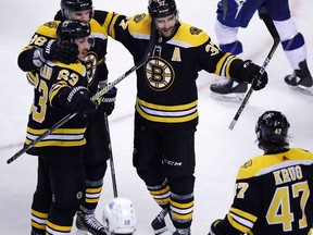 Boston Bruins center Patrice Bergeron, center, is congratulated after his goal against Tampa Bay Lightning goaltender Andrei Vasilevskiy during the third period of an NHL hockey game in Boston, Thursday, March 29, 2018.
