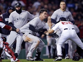 New York Yankees' Tyler Austin, center, rushes Boston Red Sox relief pitcher Joe Kelly, right, after being hit by a pitch during the seventh inning of a baseball game at Fenway Park in Boston, Wednesday, April 11, 2018. At left holding back Austin is Red Sox catcher Christian Vazquez.