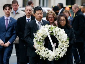 The father of Lingzi Lu, Jun Lu, foreground left, and her aunt Helen Zhao, foreground right, carry a wreath ahead of the family of Martin Richard, background from left, Henry, Bill, Denise and Jane, partially hidden, during a ceremony at the site where Martin Richard and Lingzi Lu were killed in the second explosion at the 2013 Boston Marathon, Sunday, April 15, 2018, in Boston.