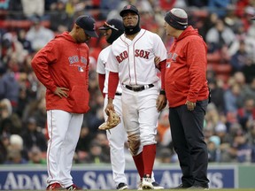 Boston Red Sox's Xander Bogaerts, center, is assisted as he leaves the field as manager Alex Cora, left, looks on in the seventh inning of a baseball game against the Tampa Bay Rays, Sunday, April 8, 2018, in Boston.