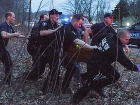 In this Tuesday evening April 24, 2018 photo, rescuers carry a young male from the Androscoggin River in Auburn, Maine to a waiting ambulance. Police in Maine say the 9-year-old boy fell into a river along with his younger brother was is in critical condition. Rescuers are searching for his 5-year-old brother.