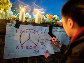 A man writes a message on a sign during a vigil for victims of the Toronto van attack, April 24, 2018 in Toronto.