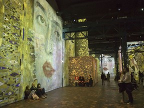 People look at the Austrian painter Gustav Klimt art projection at the l'Atelier des Lumieres gallery in Paris, France, Tuesday, April 24, 2018. A digital gallery in Paris is breaking new ground by exhibiting art as an immersive experience for visitors can walk 'inside' paintings that are vividly projected around a warehouse.