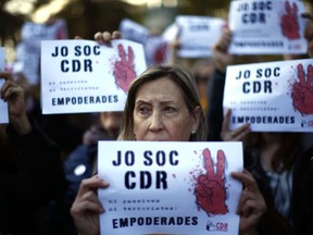 People hold placards reading in Catalan "I am CDR (Committees for the Defense of the Republic)" during a demonstration in Barcelona, Spain, Thursday, April 12, 2018. Spanish authorities on Tuesday detained seven people in Catalonia as part of a crackdown on disturbances associated with the region's attempts to secede from Spain, saying one of those arrested was suspected of terrorism. The Guardia Civil said it arrested a woman believed to be a leader of Catalonia's so-called Committees for the Defense of the Republic, a grassroots group that organizes protests. Those groups have been behind the blocking of road and train lines in Catalonia to press their demand for independence.