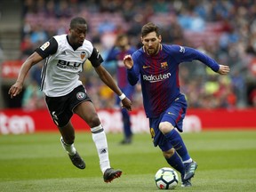 FC Barcelona's Lionel Messi, right, duels for the ball against Valencia's Geoffrey Kondogbia during the Spanish La Liga soccer match between FC Barcelona and Valencia at the Camp Nou stadium in Barcelona, Spain, Saturday, April 14, 2018.