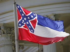 This June 23, 2015 file photo, shows the state flag of Mississippi at the Governor's Mansion in Jackson, Miss. A federal lawsuit filed Wednesday, April 4, 2018, says the Mississippi flag is "racially demeaning and hostile" because it contains the Confederate battle emblem. Several Mississippi cities and counties, and all eight public universities, have stopped flying the flag in recent years amid criticism that the Confederate emblem is a racist reminder of slavery and segregation.