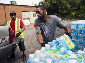 In this photo taken Aug. 11, 2017, Shawn Jones, 42, right, and Tony Price, 54, distribute bottled water at a point of distribution in Flint, Mich. Michigan will close the last four locations where Flint, Mich., residents have been getting free bottled water, filters, replacement cartridges and testing kits because the city's water quality has been below federal action levels for lead for nearly two years.