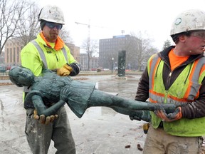 In this Monday, April 9, 2018 photo, workers with Building Restoration, Inc., remove the bronze figures of Kirk Newman's "When Justice and Mercy Prevail, Children May Safely Play" sculpture in Bronson Park in Kalamazoo, Mich. The reflecting pool will be replaced with green space.